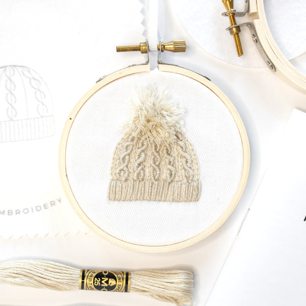Cable Knit Hat embroidery project with supplies on a white table