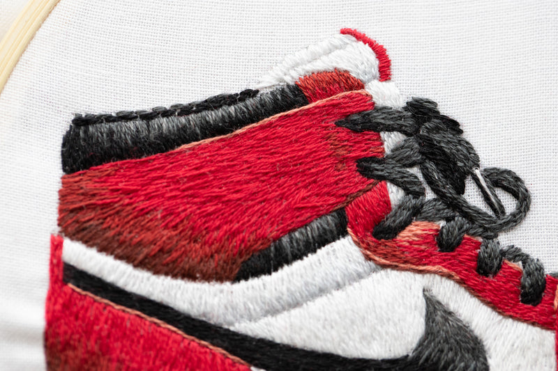Close-up details of needle painting project of sneaker in Chicago colorwary