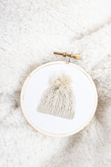 Embroidered tree ornament of knit hat on white blanket